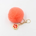 Porte-clés patte en peluche avec pompon rose-orange et fermoir doré sur fond blanc - Orange