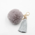 Détail d'un porte-clés boule en peluche gris-violet avec pompons et fermoir doré - Gris clair