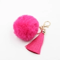 Détail macro d'un pompon en fausse fourrure rose et d'un gland en soie avec fermoir doré - Rose rouge