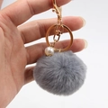 Detailansicht grauer Fellbommel Schlüsselanhänger mit goldenem Verschluss und Perle - Bommel Durchmesser 6CM / Grau