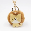 Détail d'un porte-clés chat en acrylique jaune avec pompon marron et fermoir doré - Chat brun avec balle