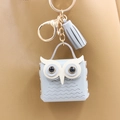 Detalle de mini monedero de búho azul claro con herrajes dorados y borla de cuero en bolso - Gris claro