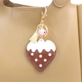 Détail d'un porte-clés fraise en cuir PU avec clochette et pompon sur un sac - Marron