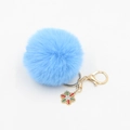 Close-up of fluffy light blue pompom keychain with golden snowflake charm and rhinestones - Blue