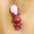 Detail eines dunkelroten gehäkelten Bären-Anhängers mit rosa Kunstfellbommel an der Tasche - Rotes Kaninchen