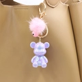 Detail showing a purple pearlescent bear charm with pink fur ball on a khaki leather bag - Purple Bear