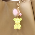 Detail of yellow pearlescent bear charm with pink fur ball and bell on a leather bag - Yellow Bear