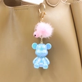 Detail of blue pearl resin bear keychain with pink faux fur ball on a beige leather handbag - Blue Bear