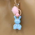Iridescent blue rabbit keychain with pink fur pompom on a brown leather handbag detail - Blue Rabbit
