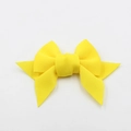 Detailed close-up of a bright yellow fabric bow accessory for shoes and bags - Yellow