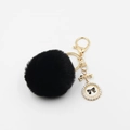 Detailed view of black faux fur pompom keychain with golden bow and pearl charm - 6cm Diameter / Black