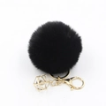 Macro detail of black faux fur pompom keychain with golden crystal geometric charm - Black