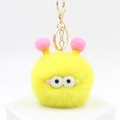 Cute yellow plush monster keychain with big eyes and pink pompom antennas on a stand - Yellow