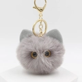 Detailopname van grijze pluchen kattenkop-sleutelhanger met goudkleurige karabijn - Grijs