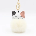 Close-up of cute lucky cat keychain with soft white pompom and golden metal ring - Off White