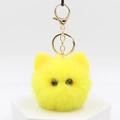 Close-up of fluffy yellow kitten plush keychain with golden metal clasp on white stand - Yellow