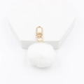 Gros plan du porte-clés pompon en fausse fourrure blanche avec fermoir doré brillant - Blanc
