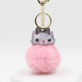 Pink cat plush pompom keychain with a polka dot bow tie on a white platform - Pink
