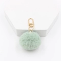 Detail of 4cm mint green faux fur pom pom keychain with gold lobster clasp on white stand - Light Green