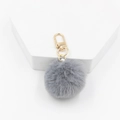 Close-up of soft grey faux fur pompom keychain with light gold metal clasp details - Gray