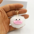 Close-up of white fluffy plush ball keychain featuring a funny pink lip expression - White