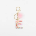 Détail du porte-clés lettre E en résine avec paillettes et pompon rose en fausse fourrure - Lettre E