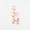 Détail du porte-clés lettre H avec paillettes en cœur et pompon en peluche rose - Lettre H