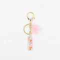 Détail du pompon rose et du porte-clés en résine avec des paillettes en forme de cœur - Lettre I