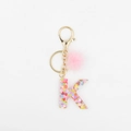 Détail du porte-clés lettre K en résine avec paillettes et pompon rose en fourrure - Lettre K