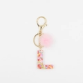 Détail de boule de poils rose et porte-clés lettre L en résine avec paillettes cœur - L