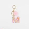 Détail du porte-clés lettre M avec paillettes colorées et pompon rose en fausse fourrure - M
