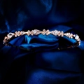 Macro-opname van roségouden metalen hoofdband met peervormige strass op blauwe zijde - Roségoud Peer Bloem Cluster Stijl (TS-J3407G)