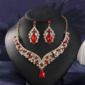 Detailaufnahme des luxuriösen Sets aus roter Edelsteinkette und Ohrringen auf Büste - Gold mit roten Strasssteinen