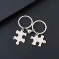 Pair of stainless steel puzzle keychains with heart magnet connection on dark background - Silver Puzzle Magnet Keychain Pair