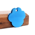 Detail van een blauwe gegalvaniseerde pootvormige penning op donker hout en wit vilt - Groot / Blauw