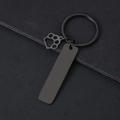 Close-up of black metal keychain featuring a rectangular plate and cat paw charm detail - 50x12mm Strip Black