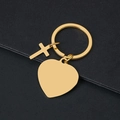 Polished gold metal heart keychain with small cross pendant on dark textured background - Heart Style / Gold