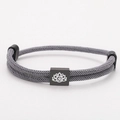 Detail of grey braided cord bracelet featuring a black square charm with white lotus and Om - Black Rope With Black Lotus