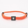 Close-up of orange braided graduation bracelet with a black 2026 Class of charm - Orange Rope + Black