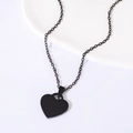 Macro shot of a minimalist black heart pendant necklace on a white ceramic plate - Heart Necklace (Black)