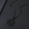 Vista macro di un ciondolo rotondo minimalista in acciaio nero su catena a maglia quadra - Nero