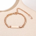 Roségoudkleurige roestvrijstalen ID-armband met rechthoekige plaat op beige ondergrond - Roségoud