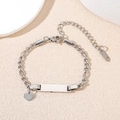 Detailed macro view of silver stainless steel Cuban chain bracelet with heart charm and ID plate - Silver