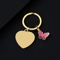 Makroaufnahme goldener Herz-Schlüsselanhänger mit rosa Glitzer-Schmetterling auf Schwarz - Gold Herz mit Schmetterling