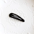 Minimalist black glossy teardrop BB hair clip with smooth enamel finish on a white tray - Black