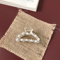 Close-up of golden hair claw with white pearls and sparkling rhinestones on fabric - Small Pearl Rhinestone Arch