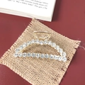 Detailed macro view of a gold metallic hair claw clip inlaid with shimmering white rhinestones - Large Rhinestone Arch