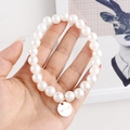 Primer plano de la pulsera de perlas blancas con una etiqueta de metal grabada HAY:LEE - Perla Pequeña Mate