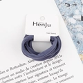 Close-up of grey-blue high-elastic hair ties on branded card with scenic background - Navy Blue