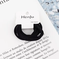 Detail of high-elasticity black hair bands on a white minimalist display card - Black